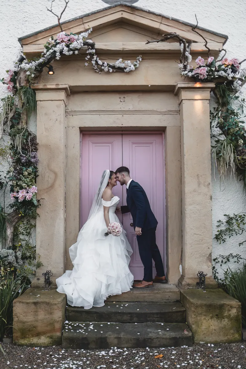 Bride and groom sharing a romantic kiss outside the wedding venue after the ceremony