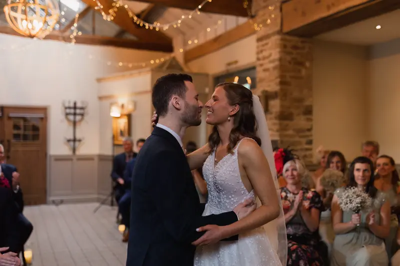 First kiss as newlyweds during rustic barn wedding ceremony in Yorkshire