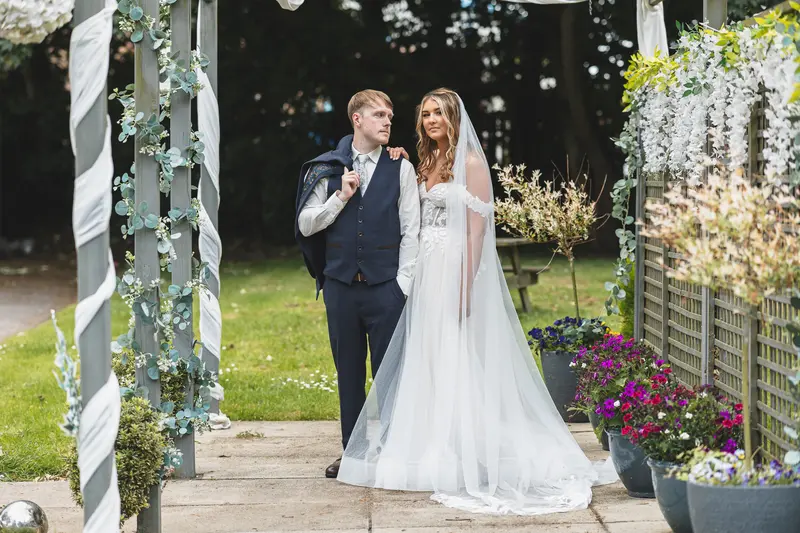 Newlyweds walking hand in hand through the wedding venue gardens