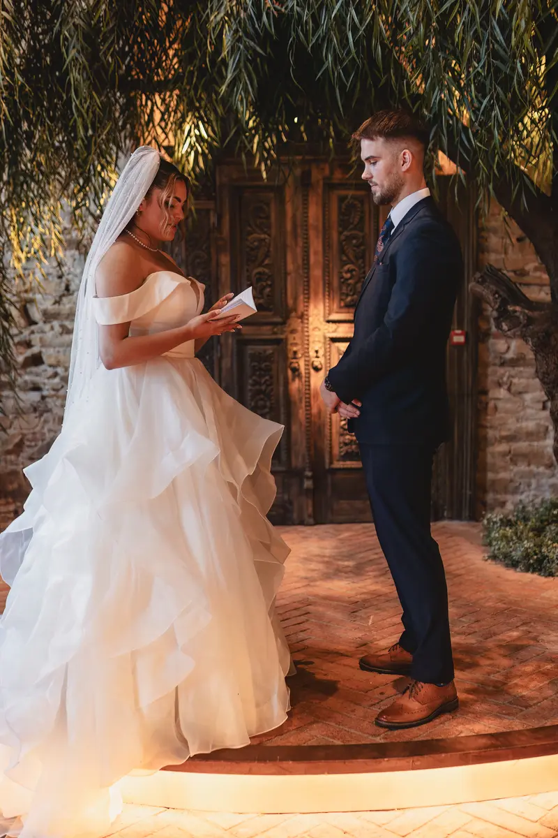 Romantic wedding vows under indoor tree at elegant ceremony venue