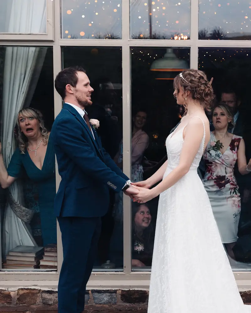 Funny candid wedding guest reactions behind bride and groom at evening reception