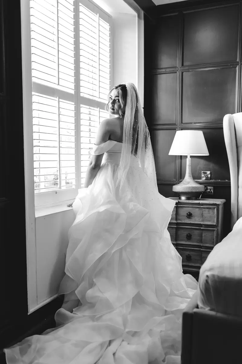 Black and white bridal portrait by the window during elegant wedding morning preparations
