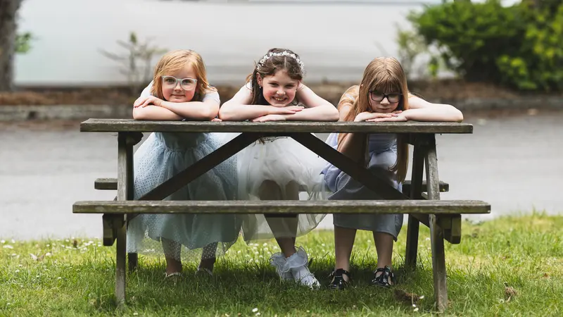Flower girls relaxing on a picnic bench during the wedding reception