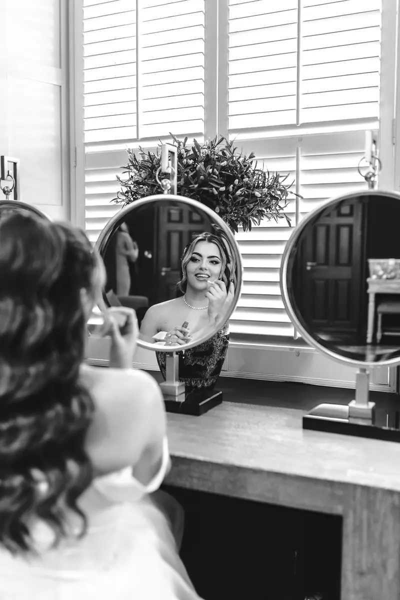 Bride smiling in the mirror while getting ready during documentary wedding photography