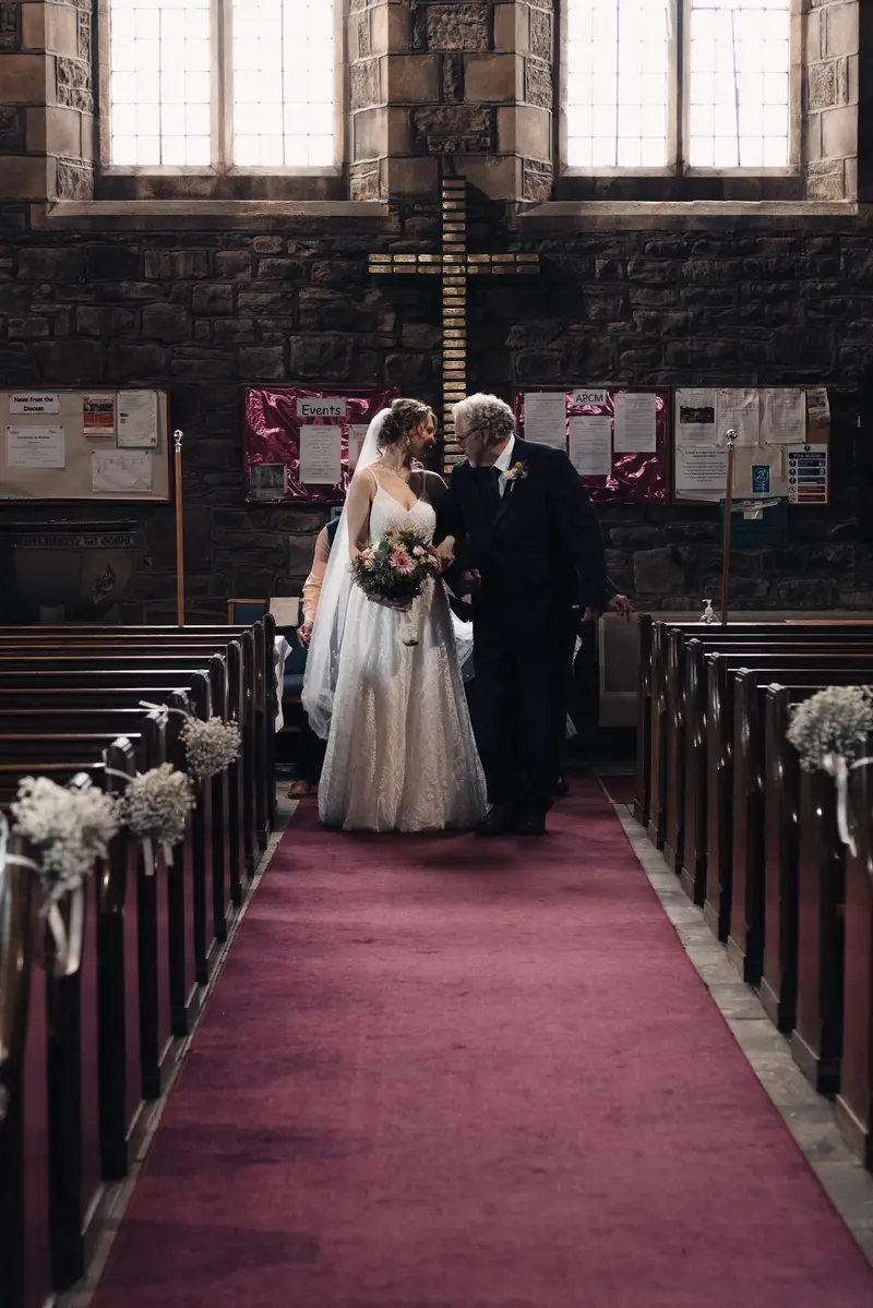 Moody church aisle entrance photograph with bride and father before ceremony