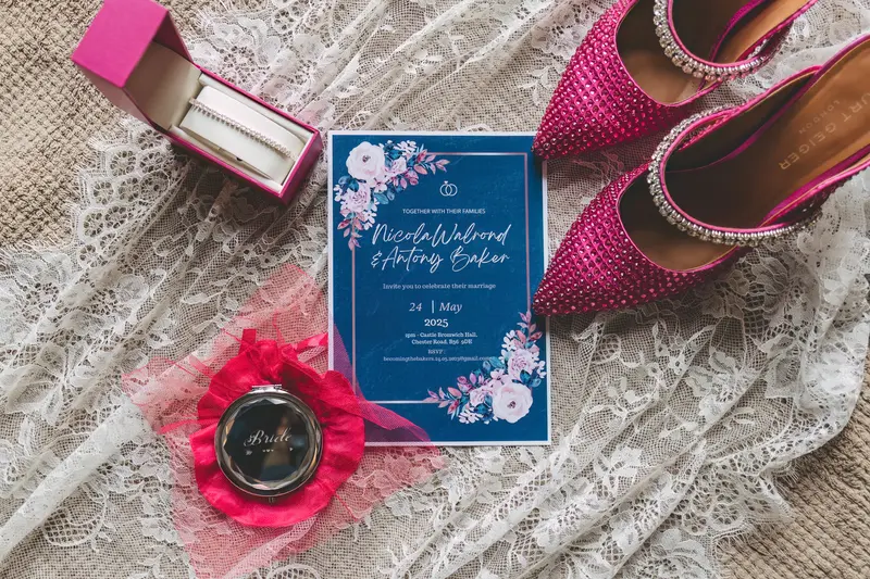 Wedding details with bridal shoes, perfume and invitation photographed during elegant bridal preparations