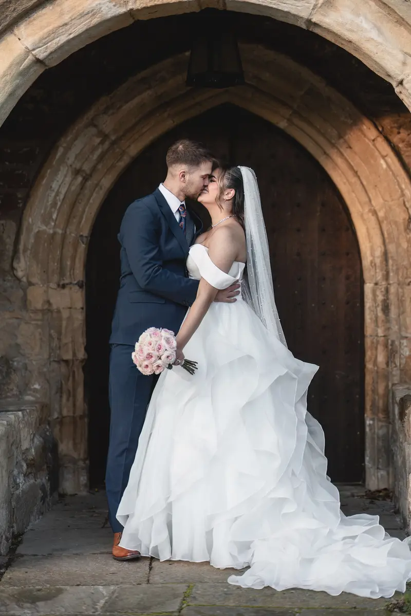 Bride and groom portraits under historic archway in West Yorkshire