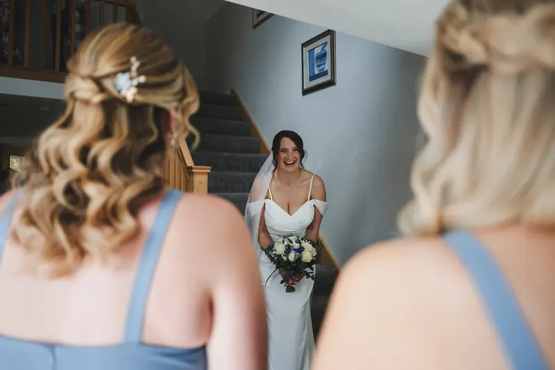 Bride laughing with bridesmaids during wedding morning preparations