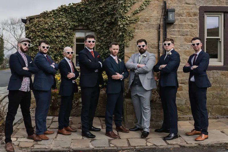 Fun groom and groomsmen wedding portrait wearing heart shaped sunglasses at rustic Yorkshire wedding venue