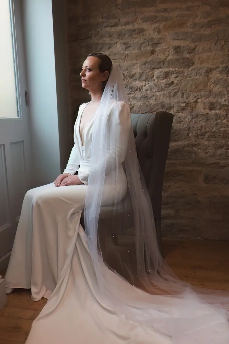 Moody bridal portrait with long veil and rustic stone wall background