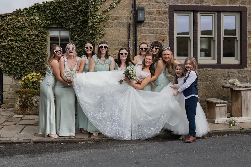 Playful documentary bridal party wedding photo with bridesmaids lifting bride in elegant Yorkshire countryside venue