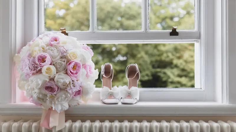 Bridal bouquet and wedding heels by window, elegant bridal preparation details, wedding photographer UK