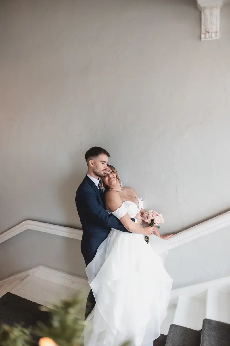 Natural staircase portrait of the bride and groom embracing after their wedding ceremony