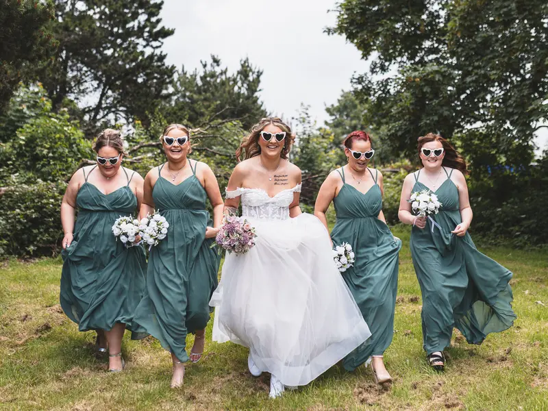 Bridesmaids running with the bride during joyful documentary wedding portraits