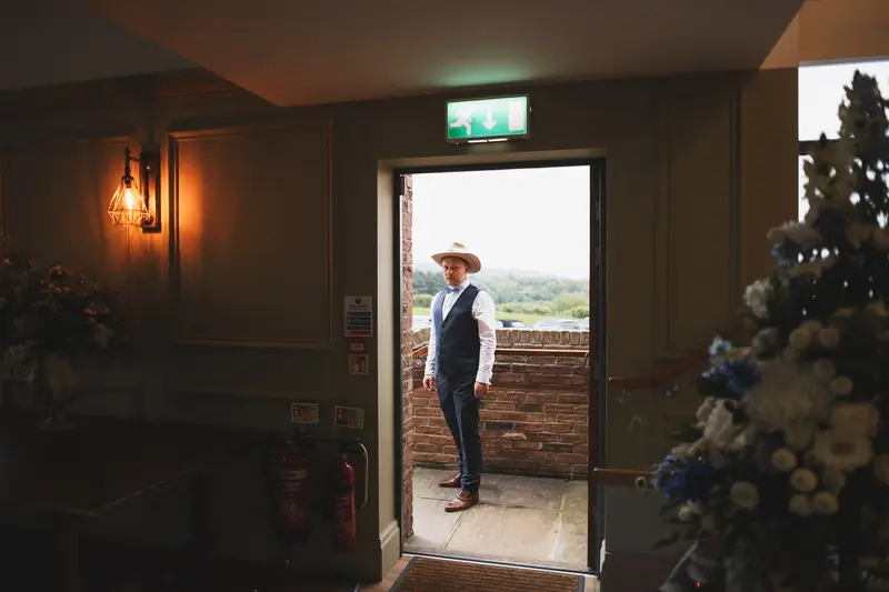 Cinematic groom portrait by doorway with dramatic wedding venue lighting