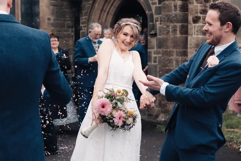 Fun candid wedding confetti moment with laughing bride and groom in Yorkshire