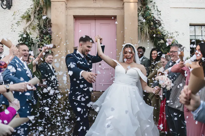 Bride and groom celebrating their confetti exit outside the wedding ceremony venue