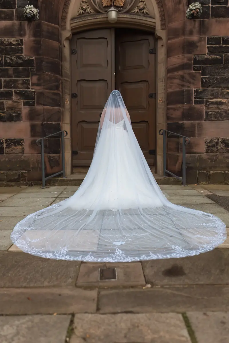 Documentary wedding photographer Yorkshire capturing elegant bridal portrait outside church entrance