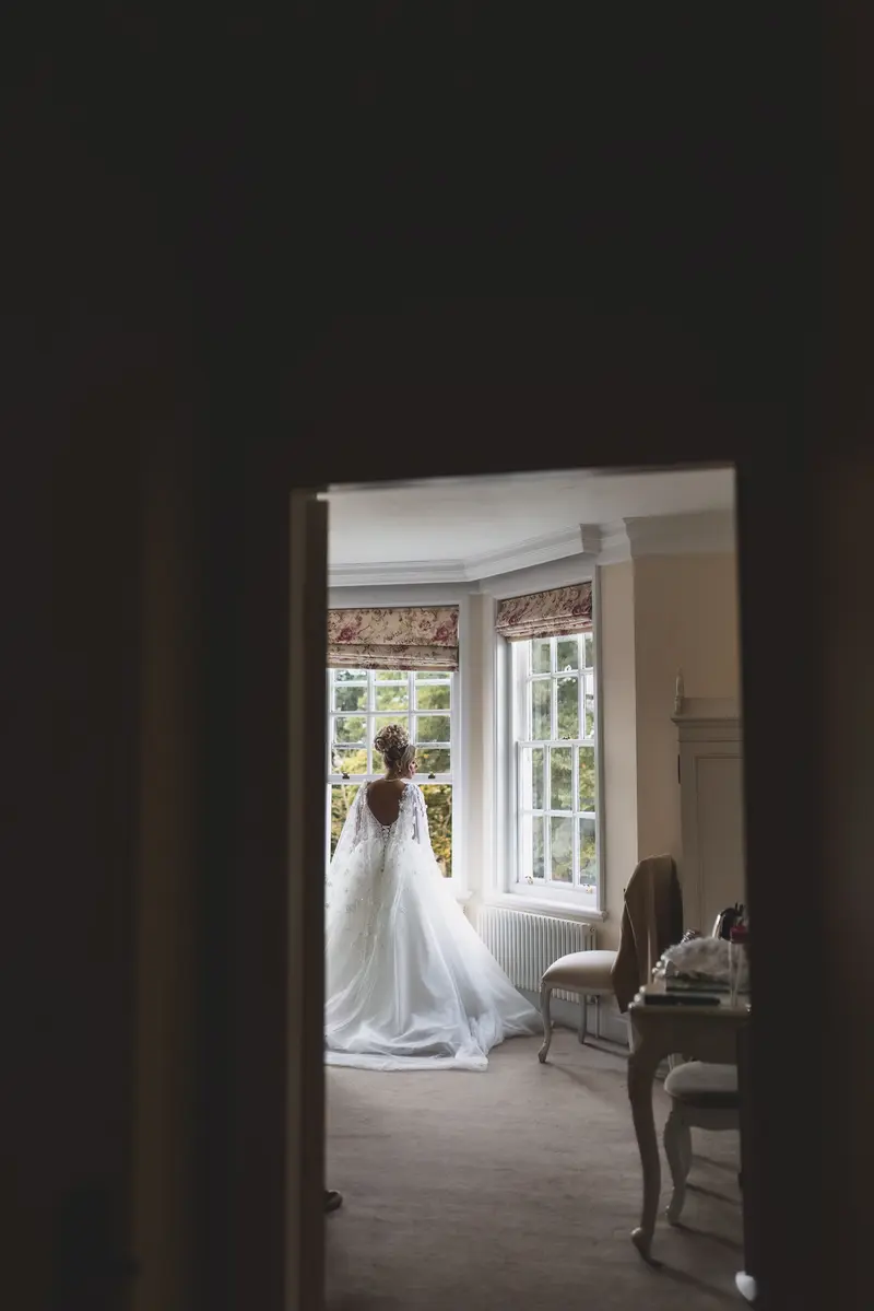 Artistic bridal portrait through doorway, creative documentary wedding photography, bridal preparation