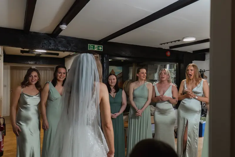Candid bridesmaids reacting to bride in wedding dress at Yorkshire wedding venue