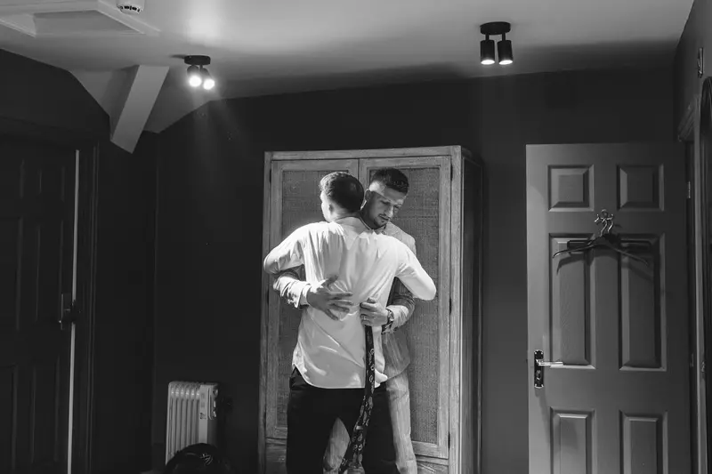 Groomsman and groom sharing an emotional hug during their wedding morning first look