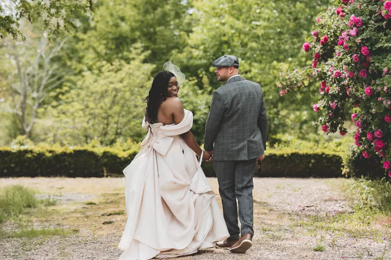 Bride and groom walking together through the gardens during relaxed wedding portraits