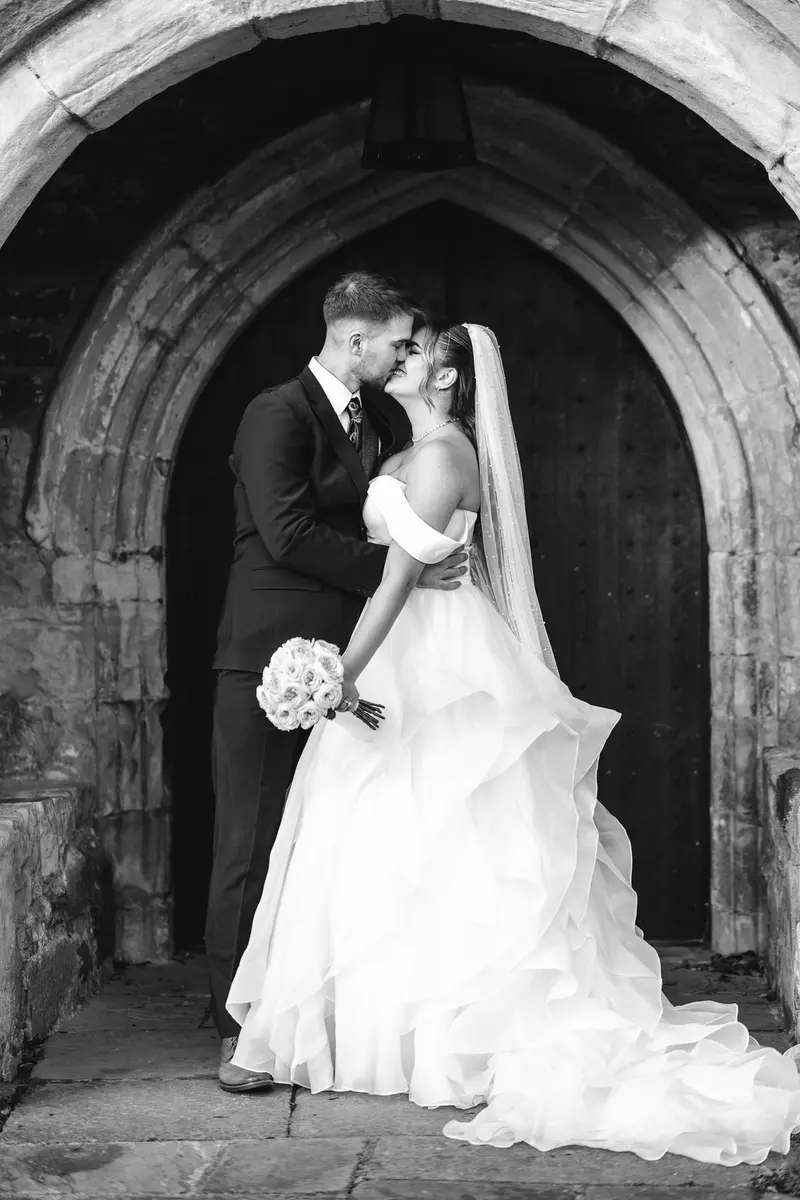 Romantic black and white portrait of the bride and groom embracing outside the wedding venue