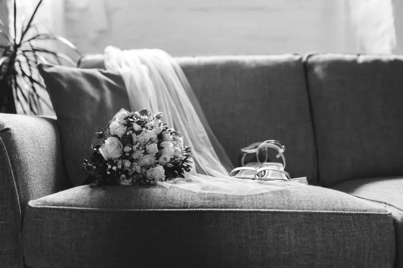 Black and white bridal bouquet, wedding veil and bridal shoes detail photograph on sofa