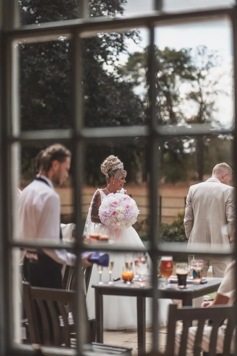 Candid wedding reception moment through window frame, natural documentary wedding photography