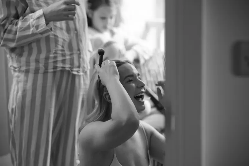 Black and white documentary bridal preparation photo with natural laughter at Yorkshire wedding