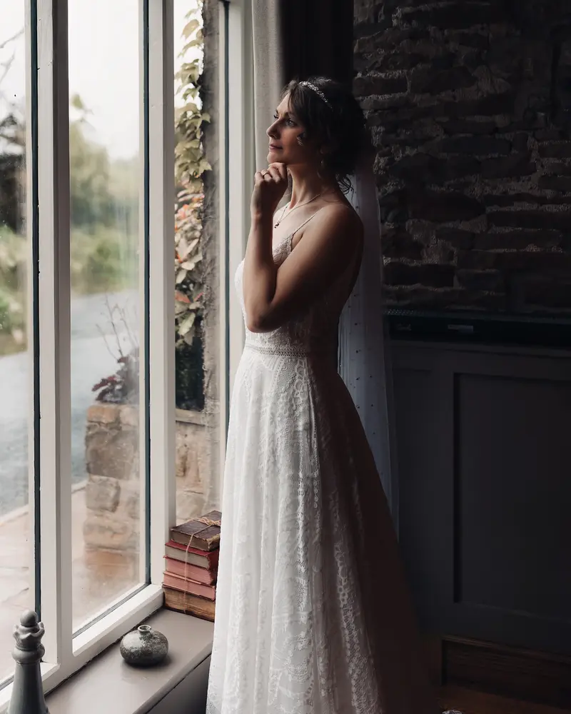 Moody bridal portrait by window with natural light and cinematic atmosphere