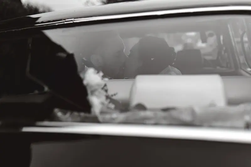 Black and white wedding kiss through vintage car window, artistic documentary wedding photography UK