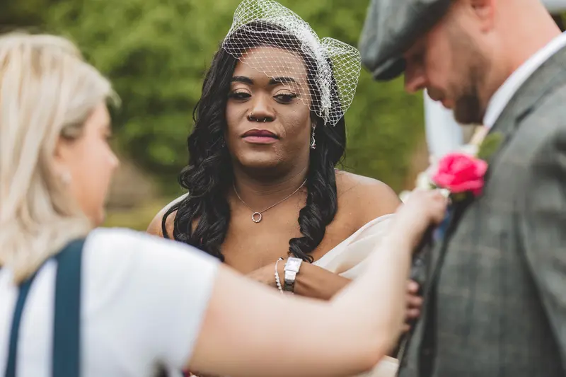 Bride having her dress adjusted before the outdoor ceremony begins
