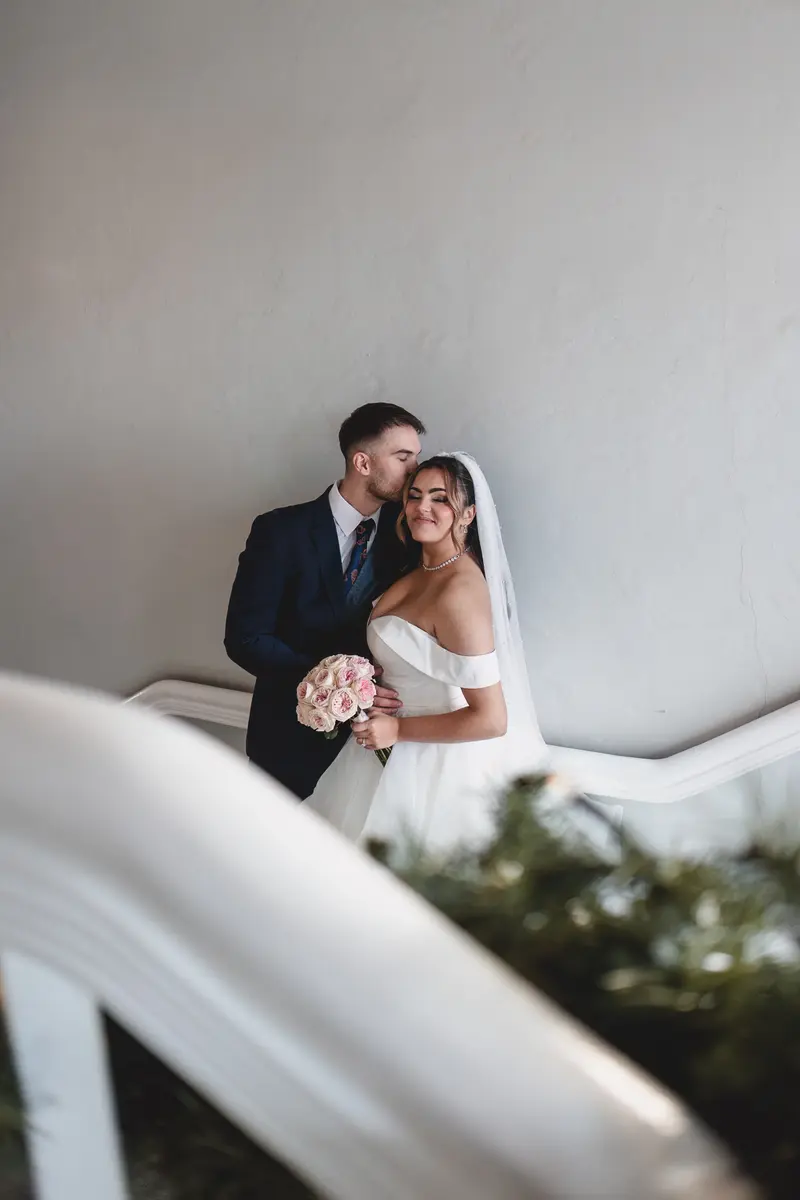 Bride and groom sharing an intimate embrace on a staircase during romantic wedding portraits