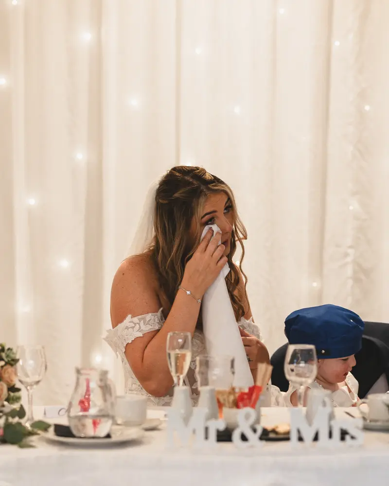 Emotional bride wiping away tears during heartfelt wedding speeches