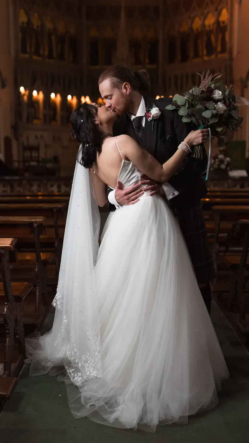 Romantic wedding kiss inside church with dramatic candlelight, Yorkshire wedding photography