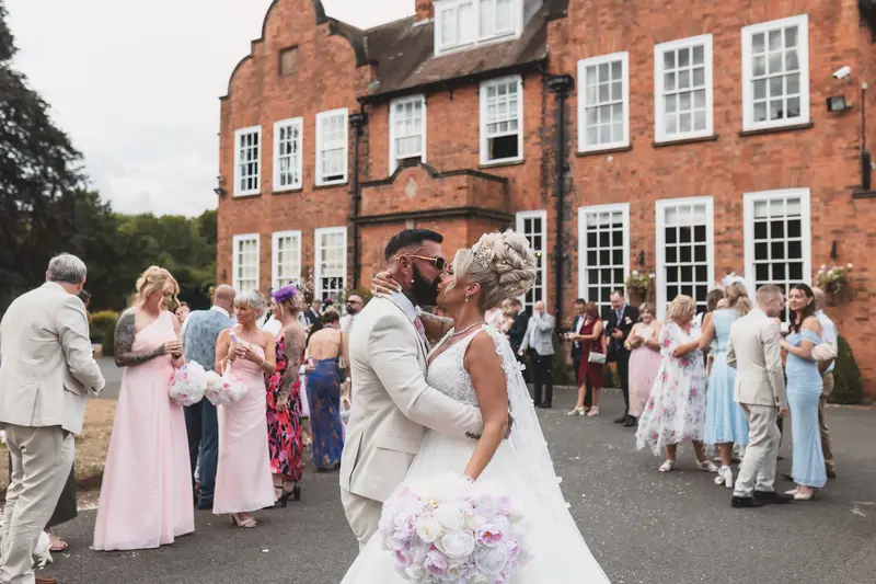 Newlywed couple kissing outside luxury manor wedding venue