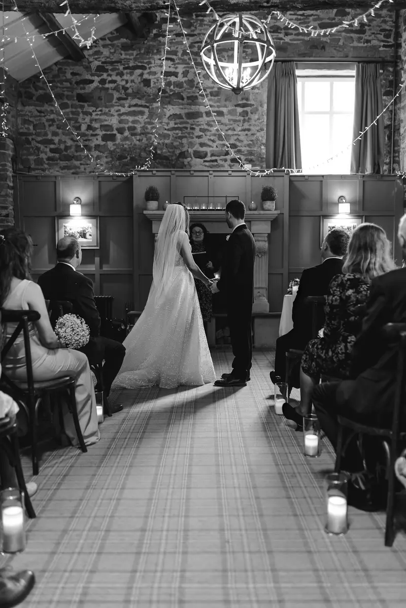Black and white documentary wedding ceremony photo with rustic Yorkshire venue lighting